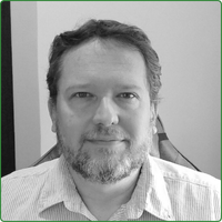 A black and white head shot of Pieter Botha, sitting in an office space